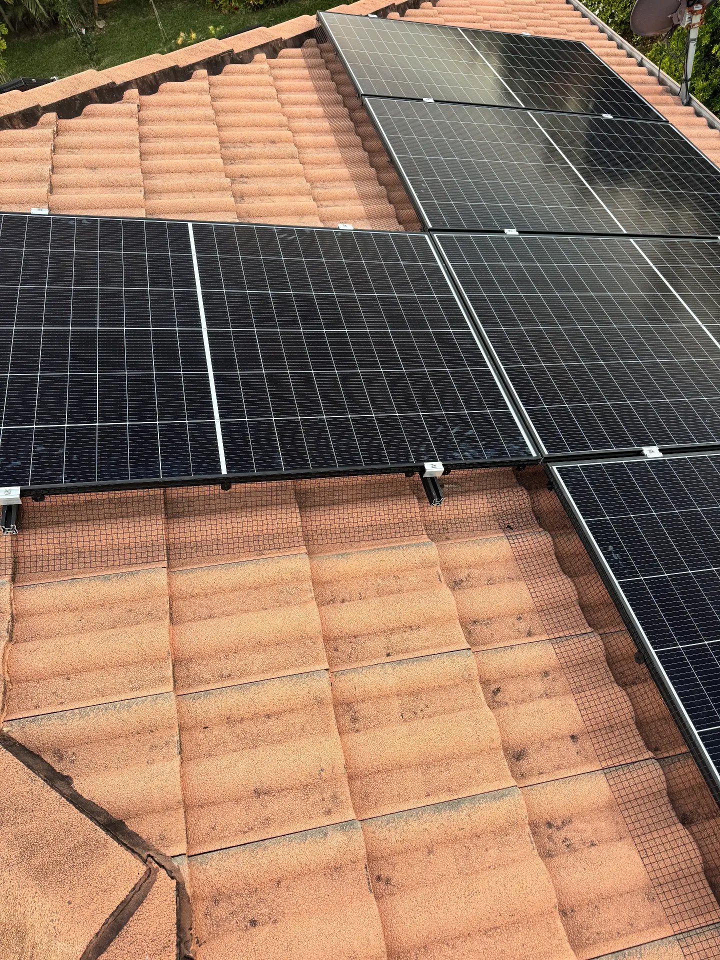 Bird mesh protection installed around solar panels on a terracotta tiled roof