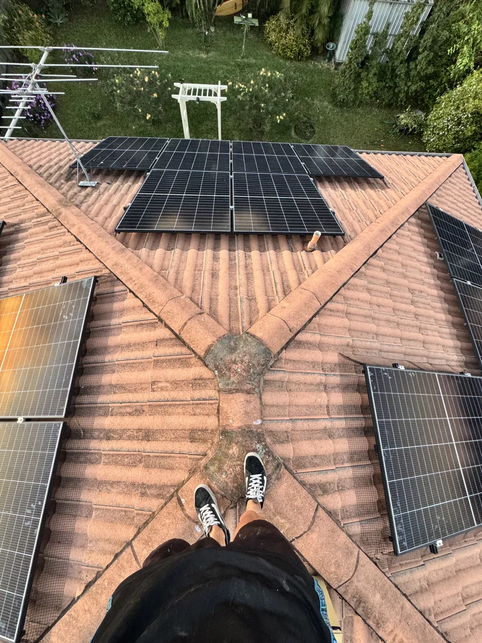 Overhead view of solar panels with bird mesh on a terracotta tiled roof